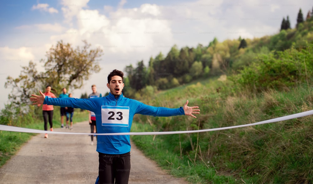 Um corredor homem cruzando a linha de chegada em uma competição de corrida na natureza.