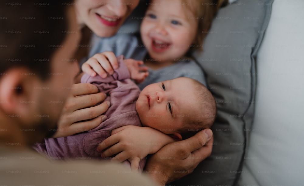 A happy young family with newborn baby and little girl enjoying time together at home.