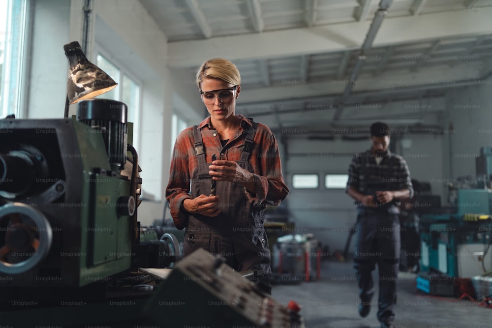 A portrait of young industrial woman working indoors in metal workshop.