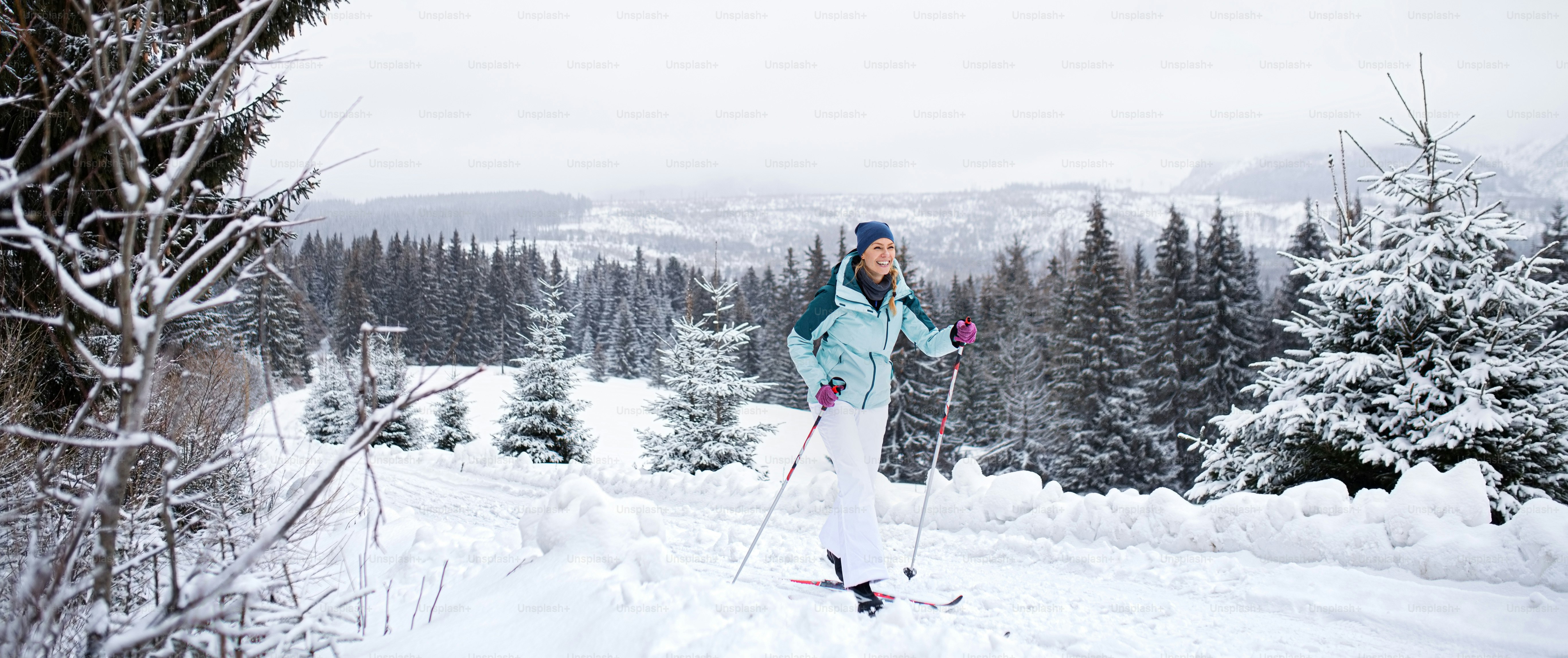 A happy mid adult woman cross country skiing outdoors in winter nature, Tatra mountains Slovakia.