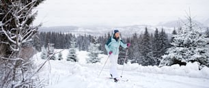 A happy mid adult woman cross country skiing outdoors in winter nature, Tatra mountains Slovakia.