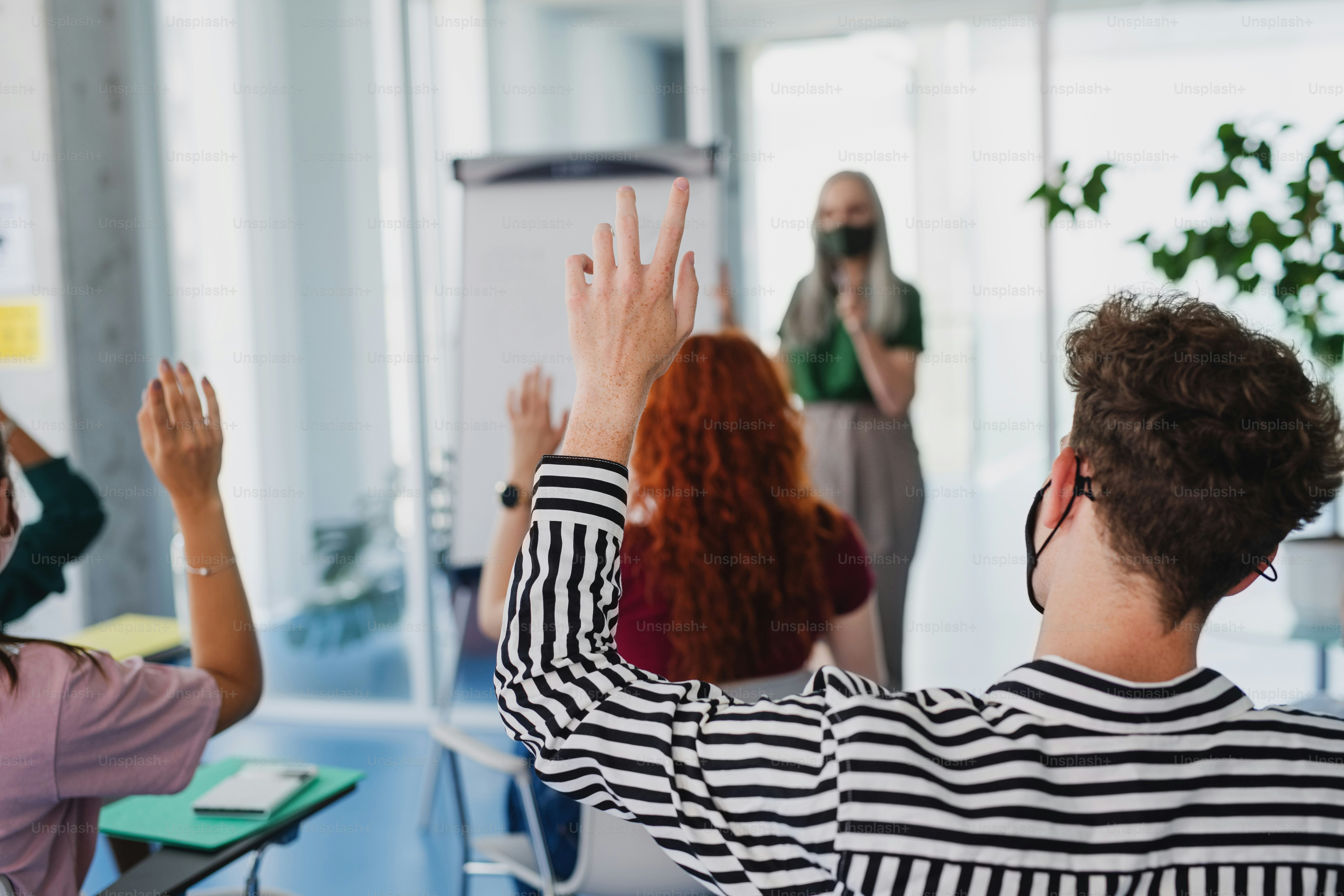 A rear view of university students with teacher studying indoors ...