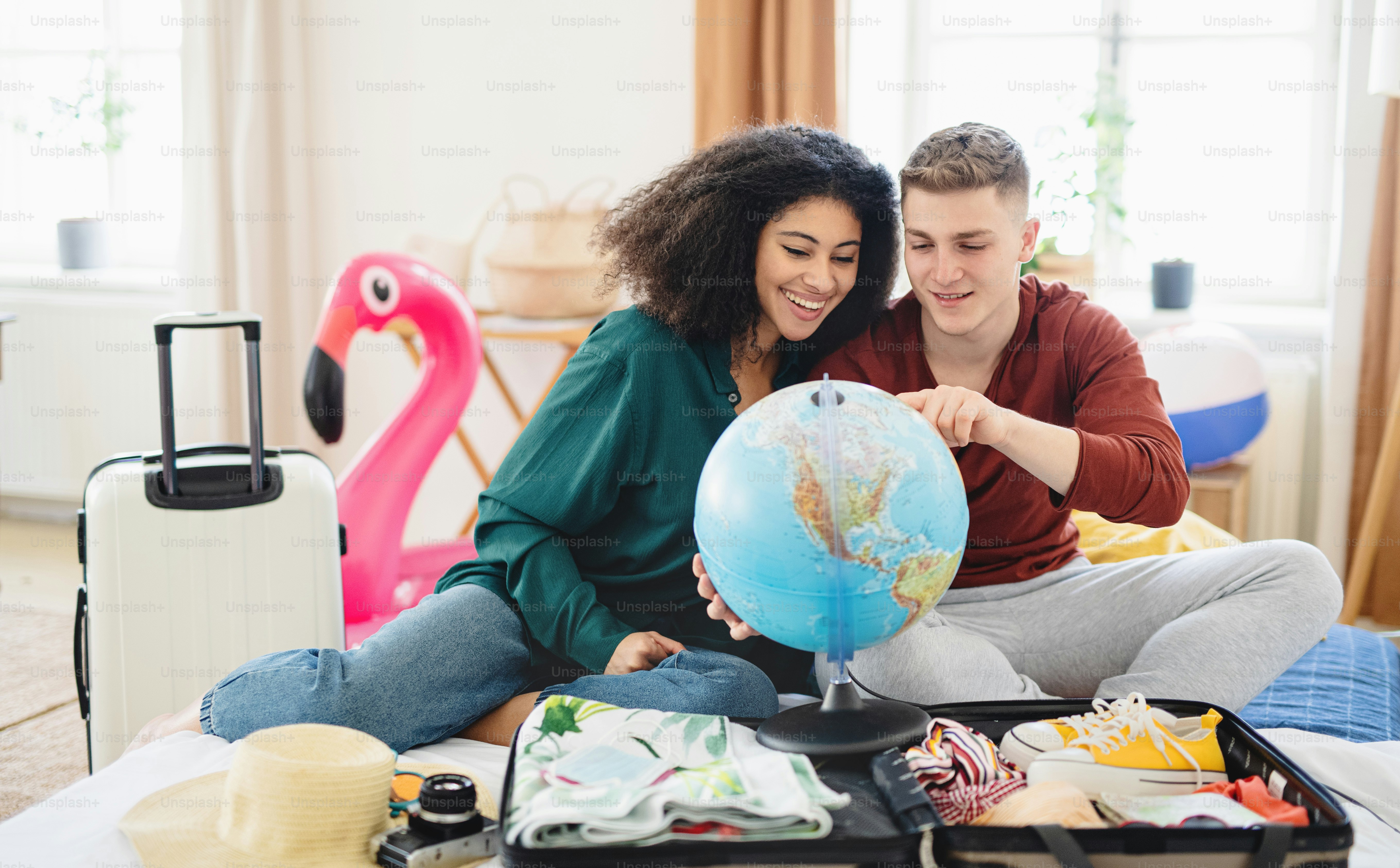 Pareja joven feliz con mapa empacando para vacaciones en casa.