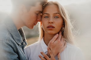 Side view of young couple on a walk in nature at sunset in countryside, hugging.