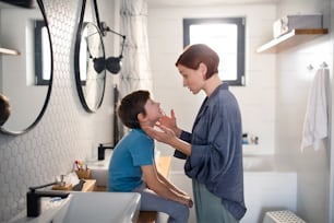 Une mère parle avec son petit garçon dans la salle de bain à la maison.