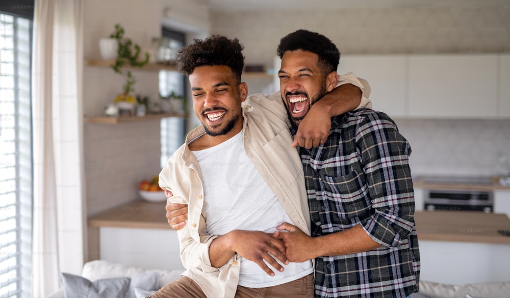 Jovens irmãos adultos rindo na cozinha dentro de casa, se divertindo.