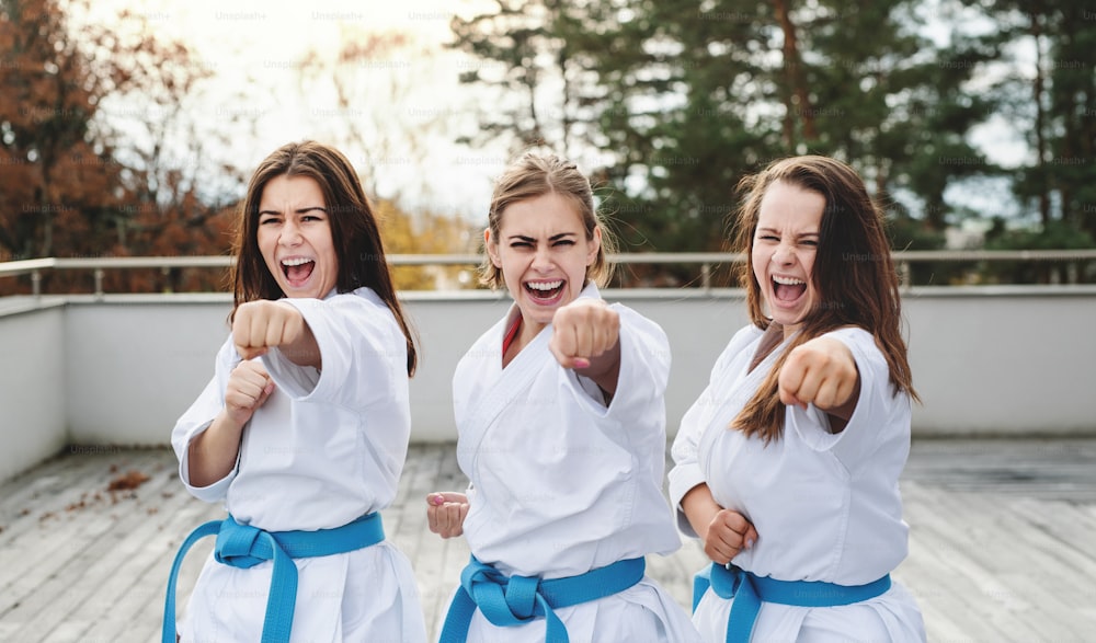 Un grupo de mujeres jóvenes practicando karate al aire libre en una terraza.