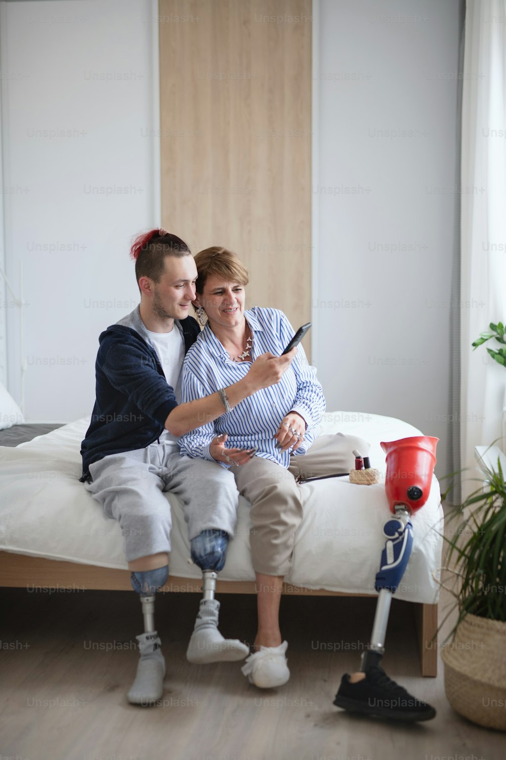 Happy disabled people taking selfie on bed indoors at home, leg amputee and prosthetic concept.