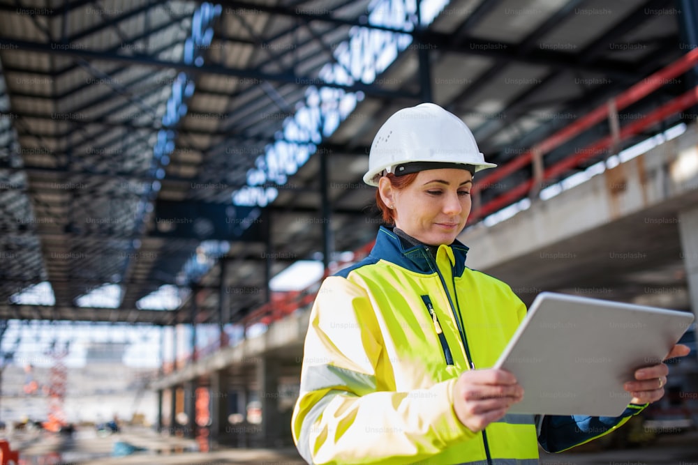 Une femme ingénieure avec une tablette debout sur un chantier de construction, en train de travailler. Espace de copie.