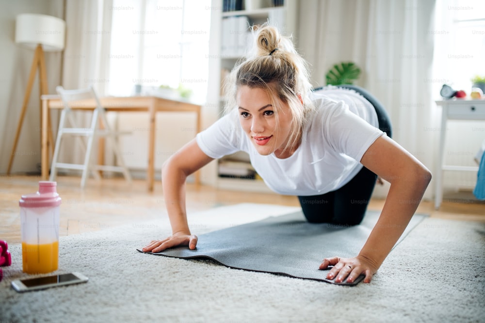 A young woman doing exercise on the floor indoors at home.