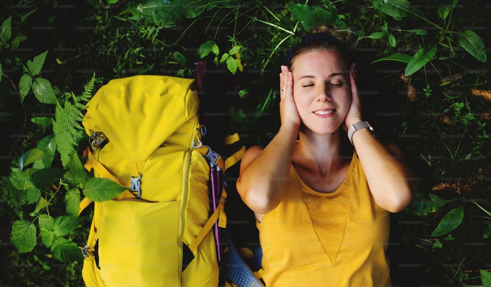 Vista superior de una mujer excursionista feliz acostada en el suelo al aire libre en el bosque, descansando.