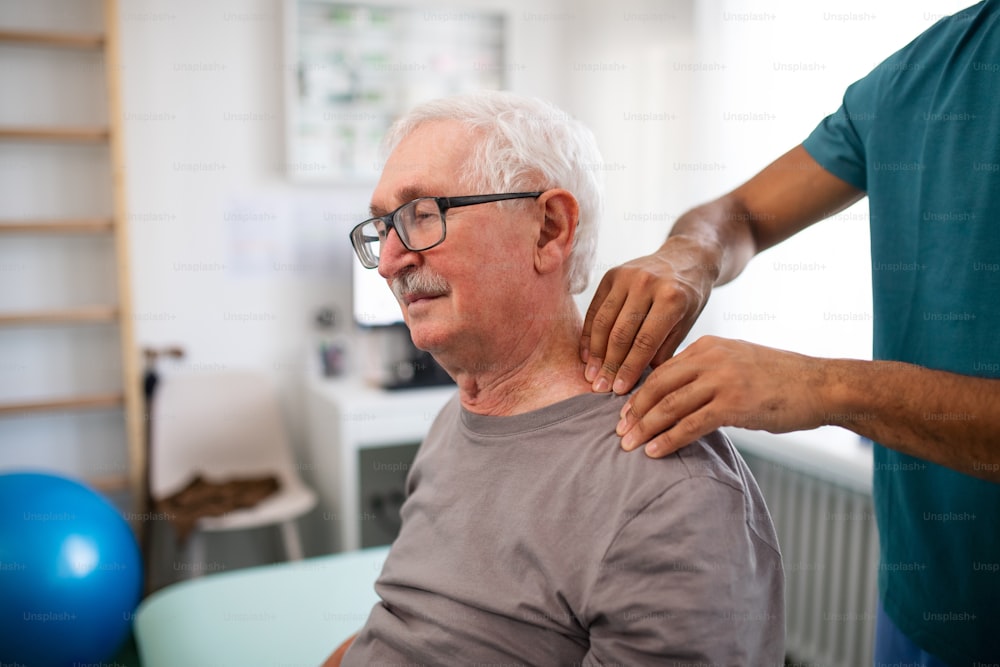 A young physiotherapist massaging the neck of senior patient in a physic room