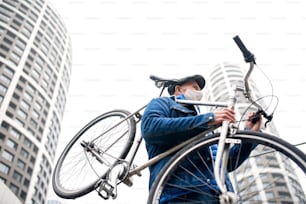 市内の路上で自転車を屋外に運ぶ年配の男性、コロナウイルスのコンセプト。