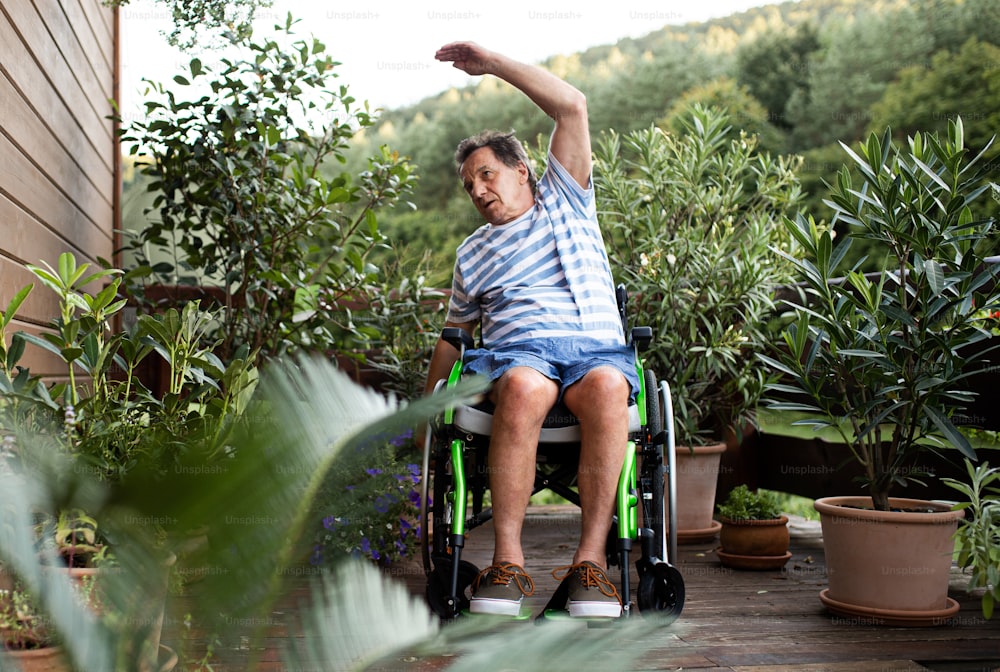 Um homem idoso em cadeira de rodas fazendo exercício no terraço.
