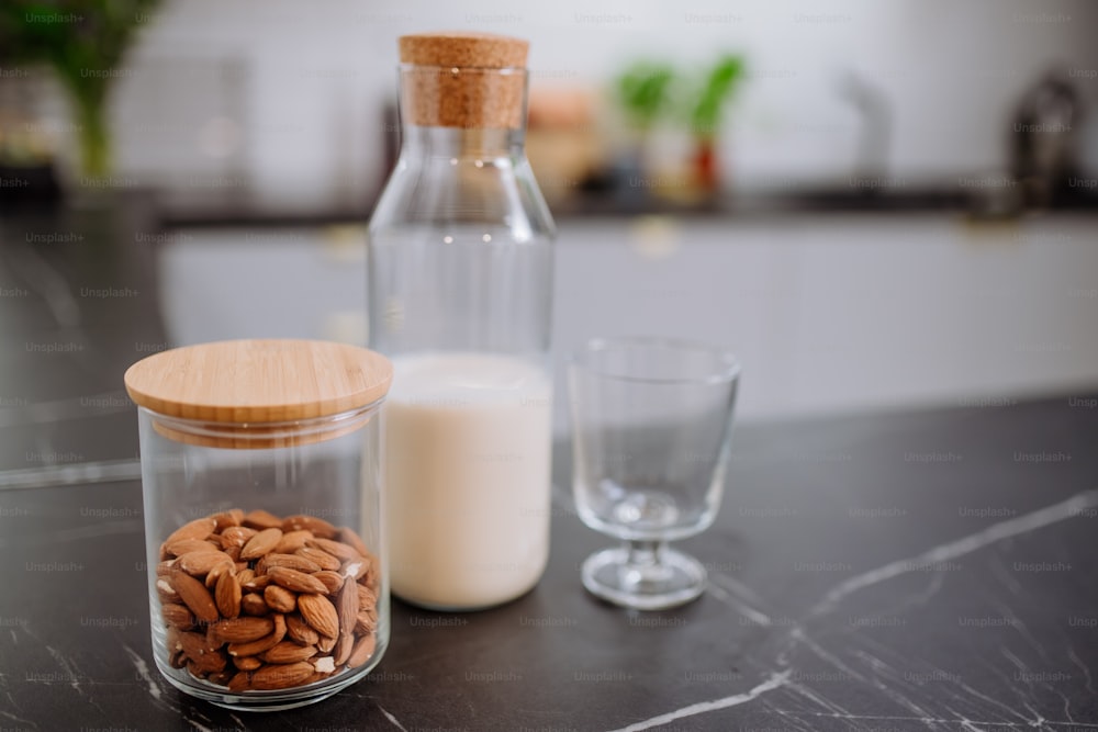 Una leche de almendras y un vaso en la encimera de la cocina. Concepto de producto vegano saludable.