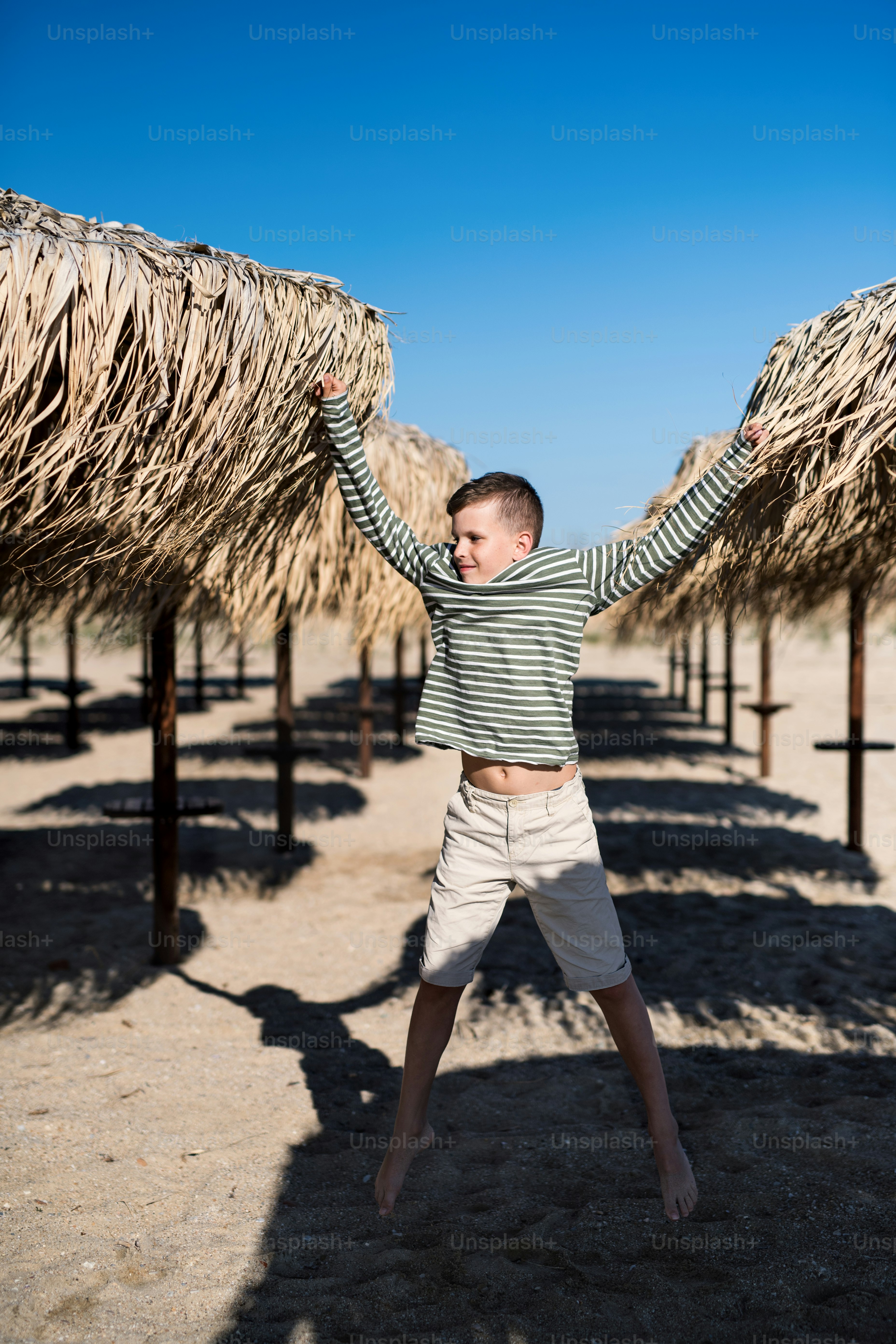 A cheerful small boy playing outdoors on sand beach, jumping. photo ...