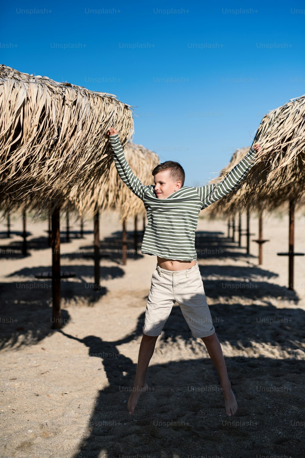 A cheerful small boy playing outdoors on sand beach, jumping.