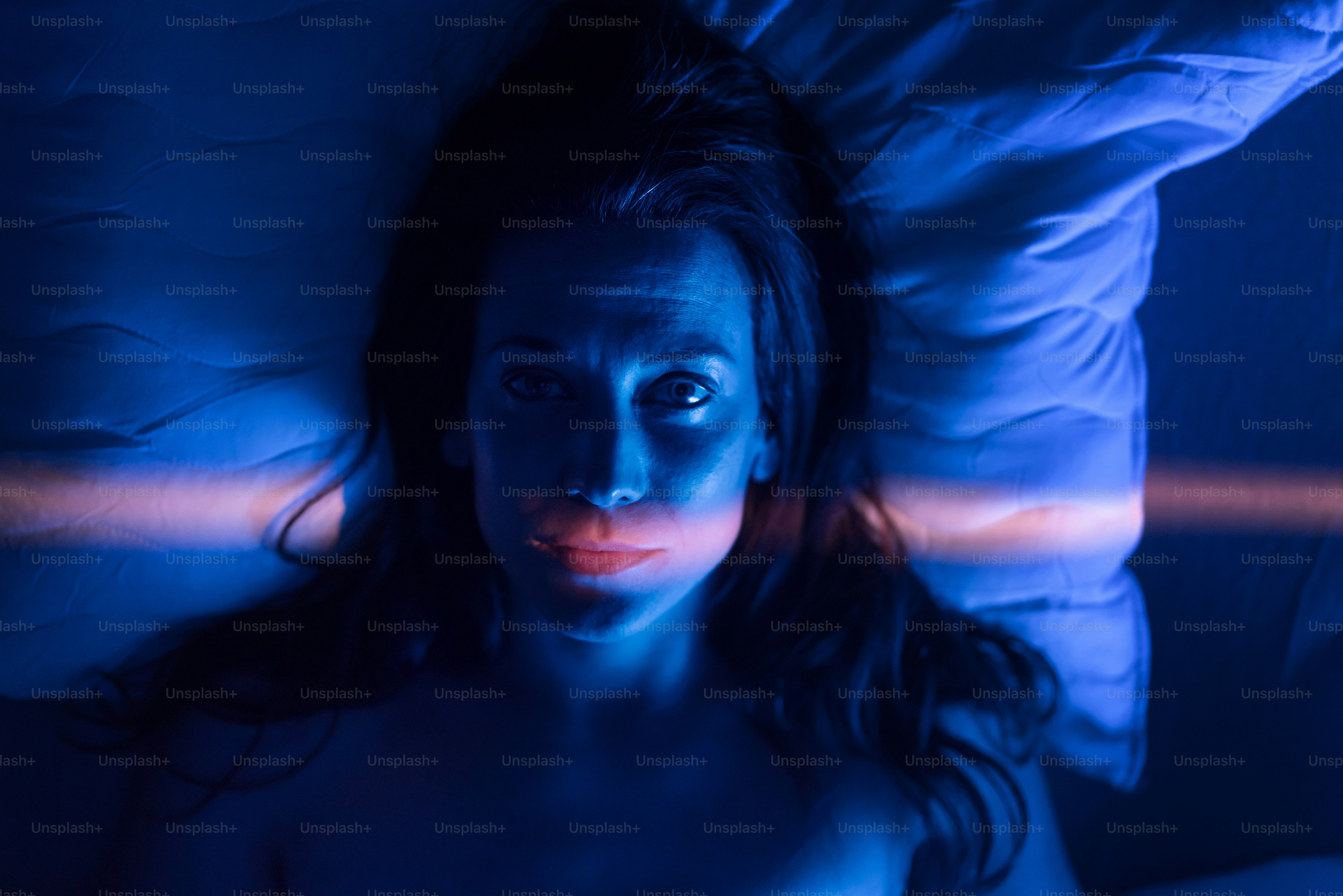 不眠症とうつ病に苦しむ孤独な女性が、夜ベッドで眠れずに横たわっているクローズアップ。
