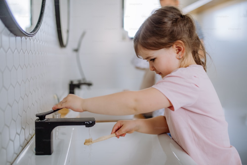 Una bambina che si lava i denti in bagno, concetto di routine mattutina.