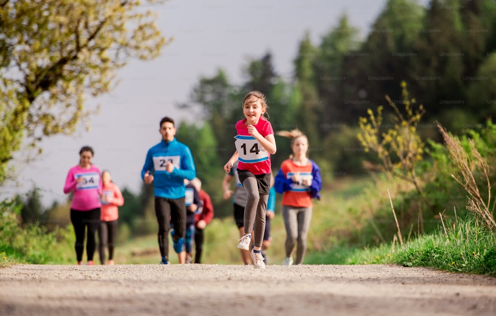 A large group of active multi generation people running a race competition in nature.