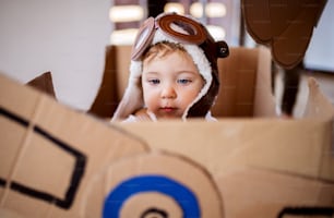 Una bambina con l'aereo del cartone e le nuvole che giocano all'interno a casa, concetto di volo.