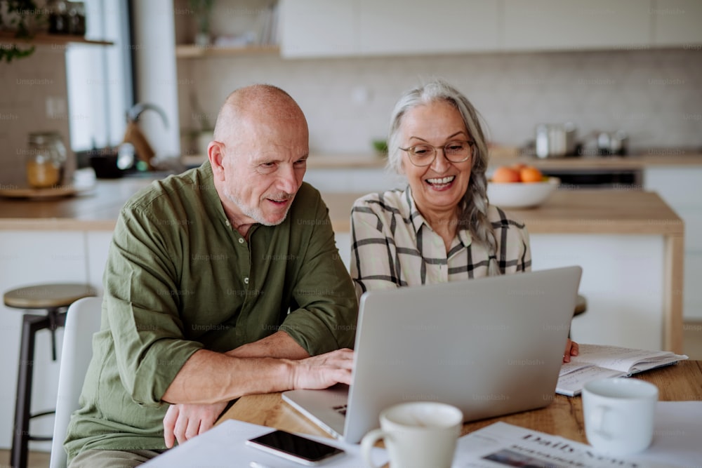 A happy senior couple calculate expenses or planning budget together at home.