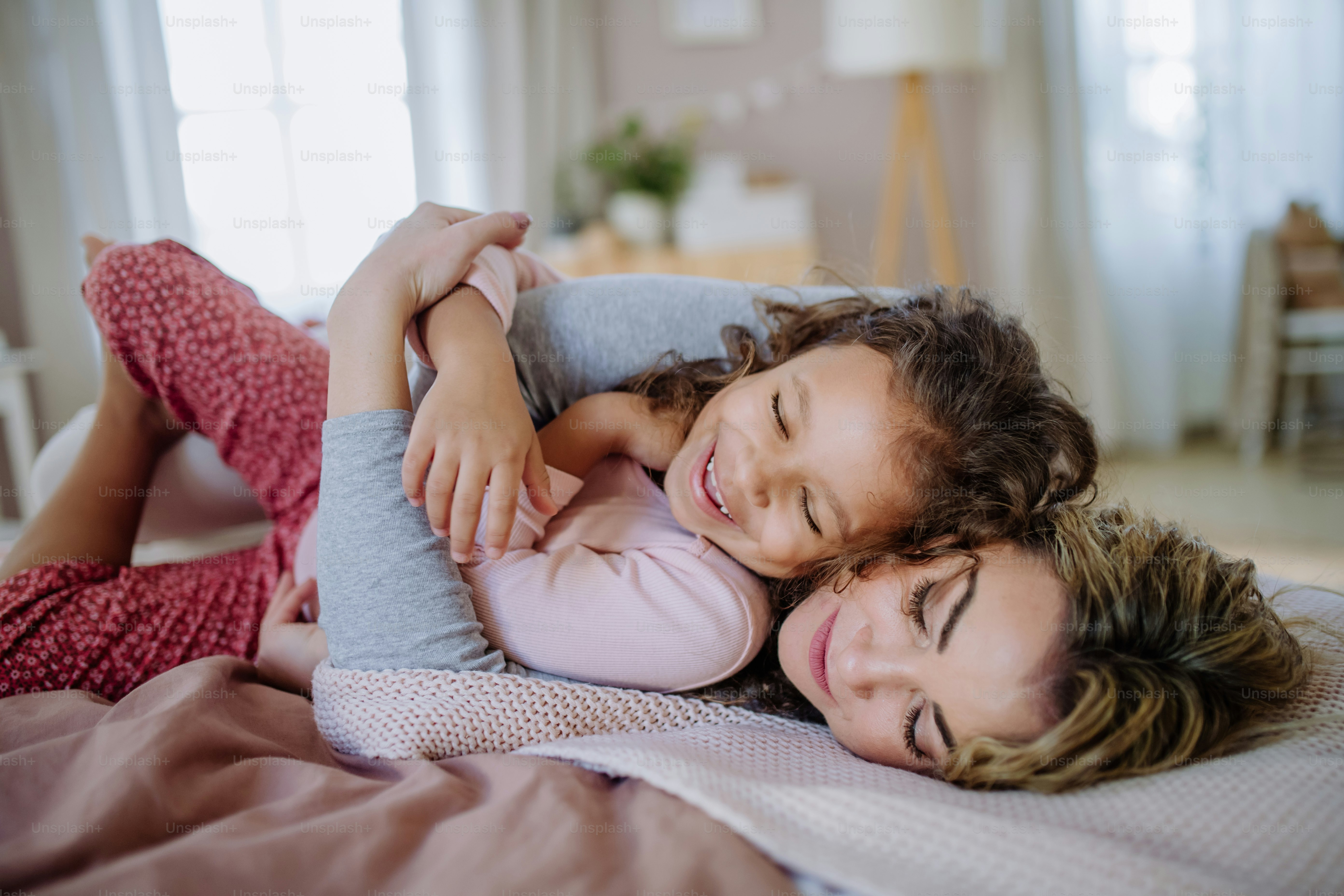 Foto Una madre feliz acostada en la cama con su pequeña hija y ...