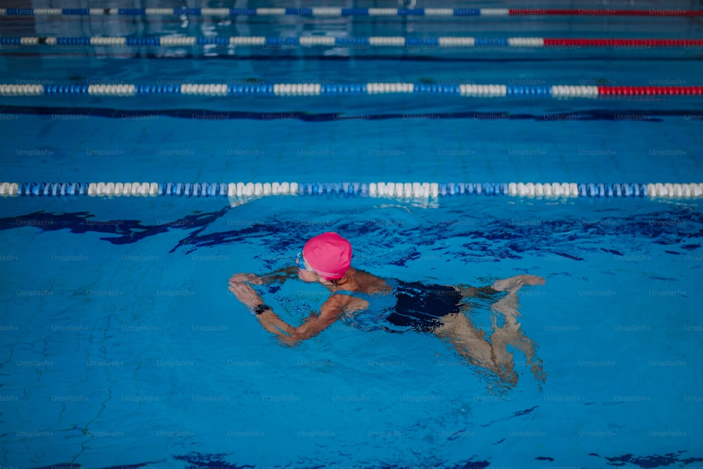 Uma visão de alto ângulo da mulher idosa ativa nadando em piscina interior.