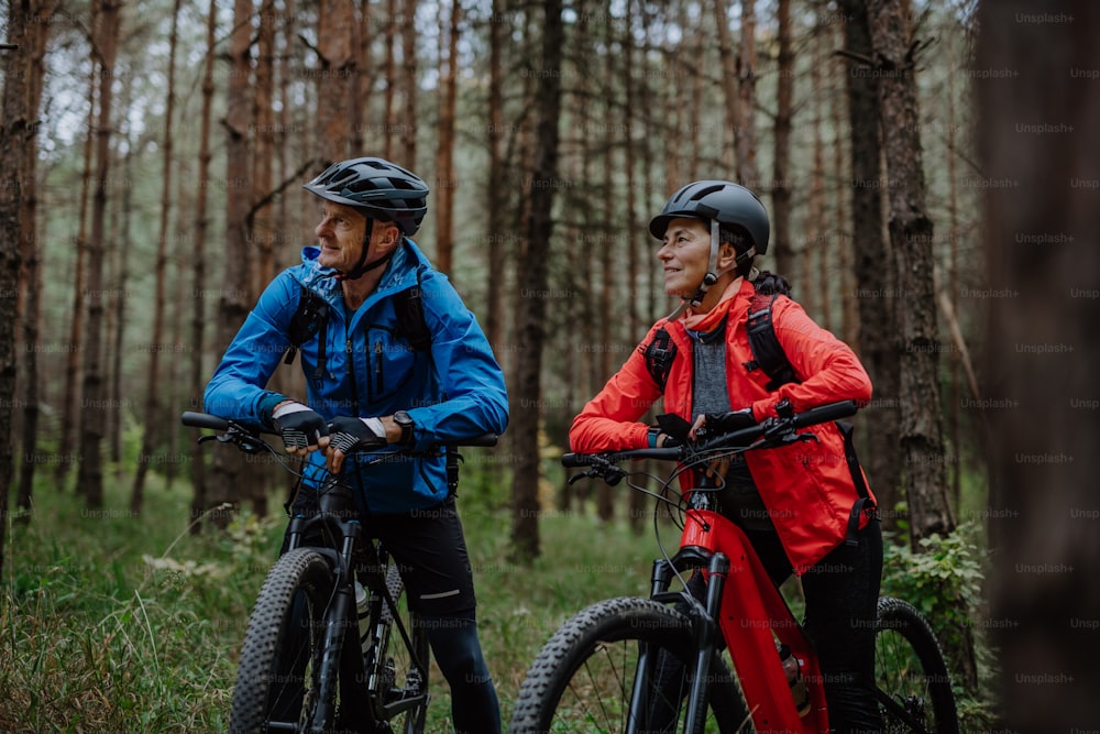 A senior couple bikers with e-bikes admiring nature outdoors in forest in  autumn day. photo – Bicycle Image on Unsplash