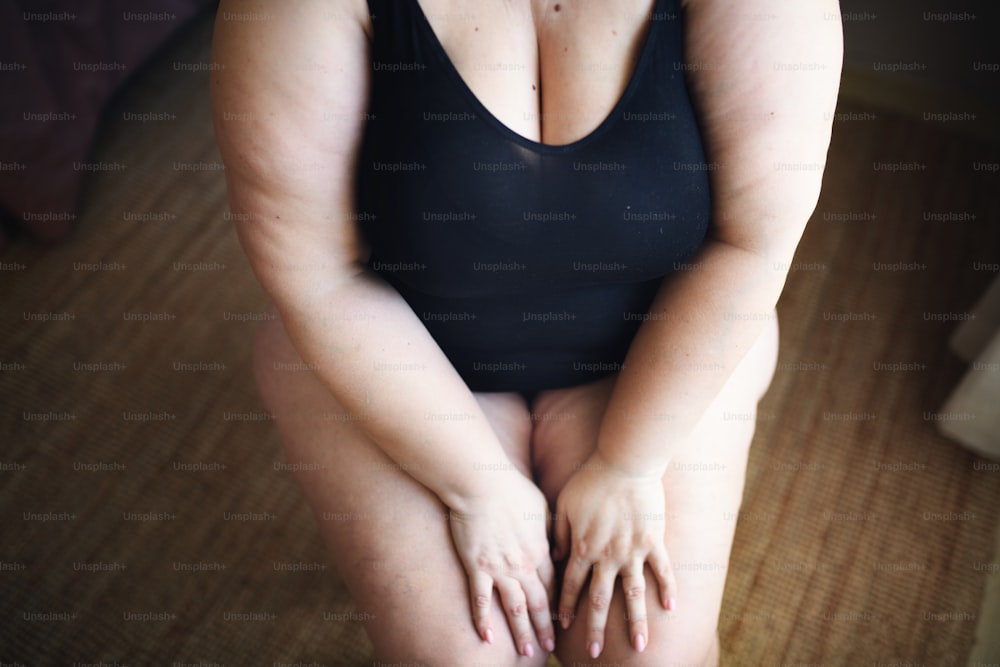 A midsection of fat woman in underwear sitting.