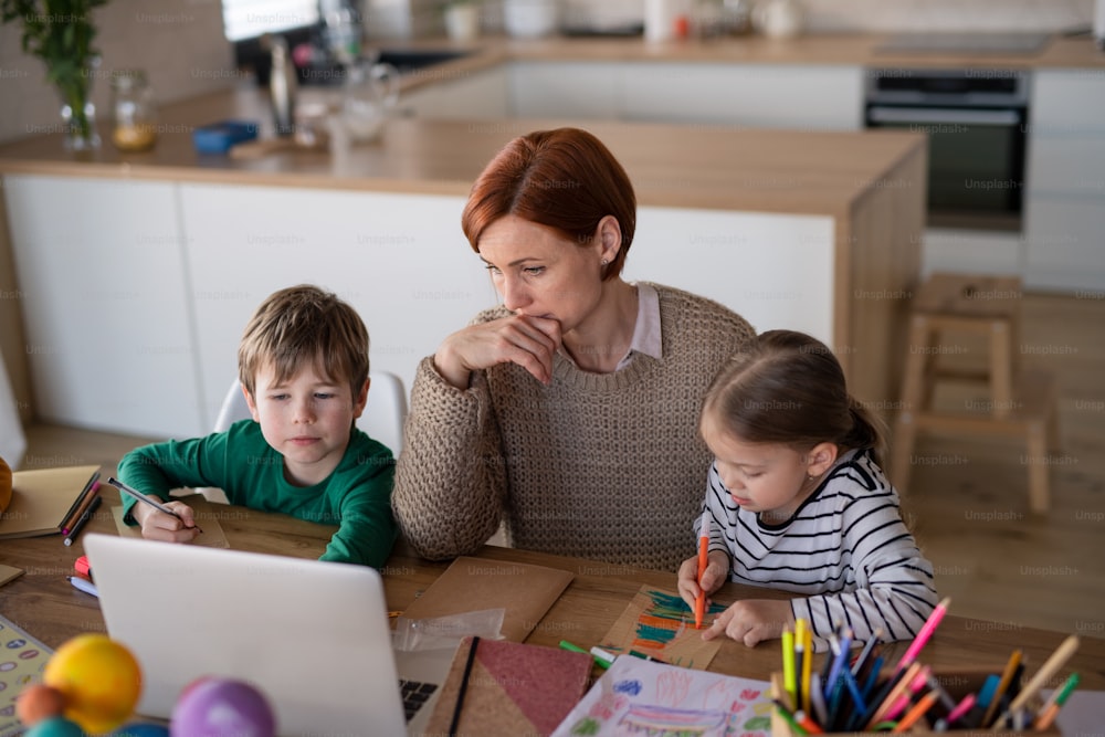 A mother of little children supervising them when distance learning and doing homework at home.