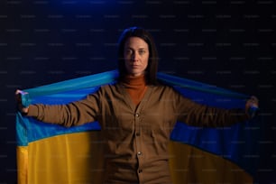 Mujer triste cubierta con la bandera de Ucrania