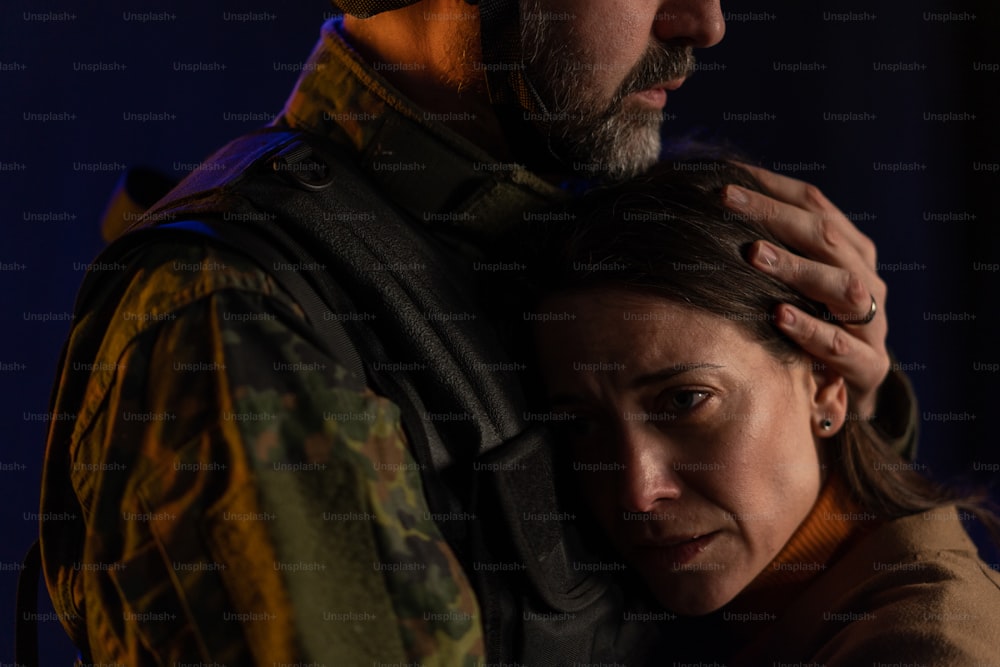 Um close-up de mulher triste chorando ao abraçar seu marido militar e dizer adeus a ele.