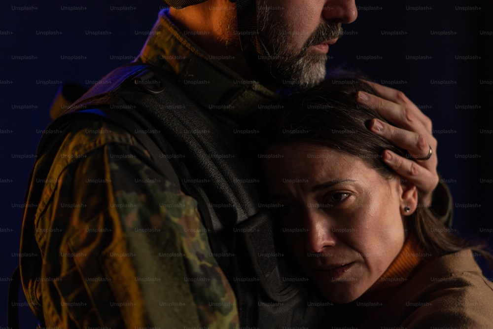 A close-up of sad woman crying when hugging her military husband and saying-goodby to him.