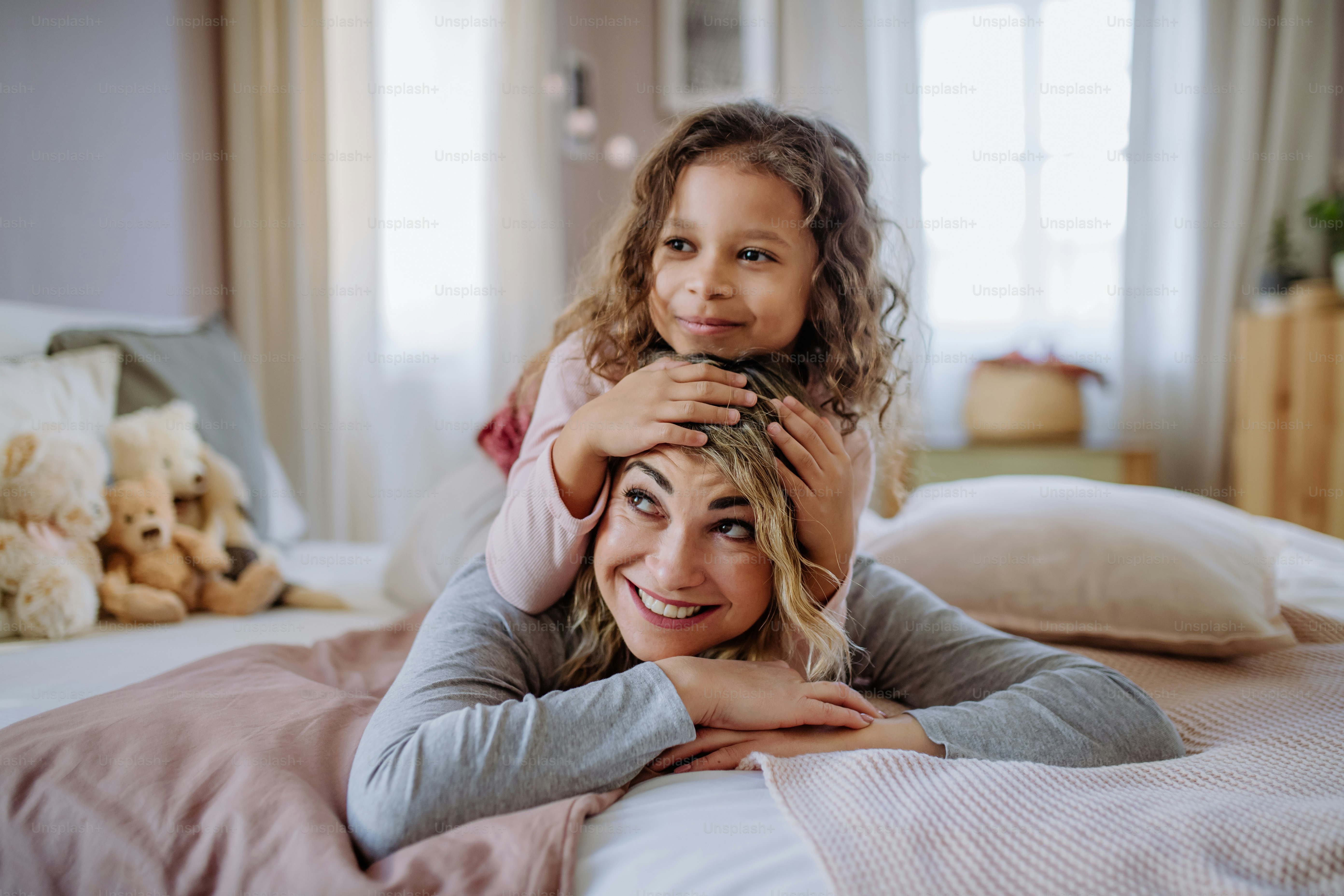 Foto Una niña feliz acostada sobre la espalda de la madre en la cama y ...