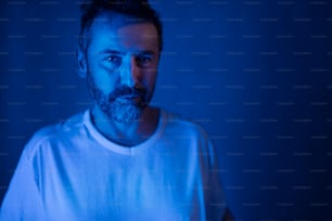 Head and shoulders view of bearded man in dark environment.