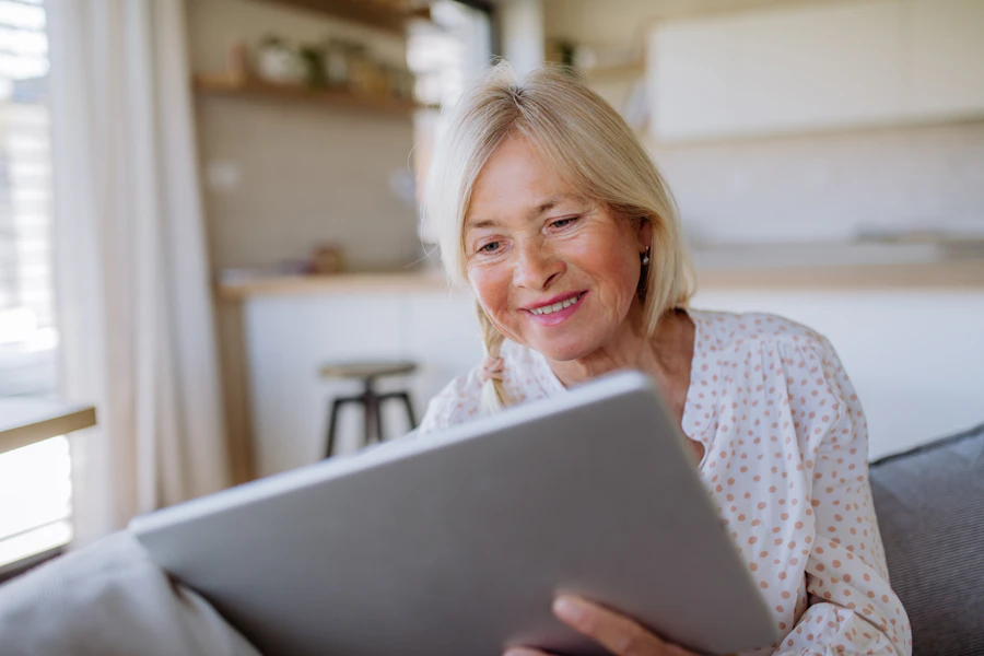 Senior woman sitting on sofa using tablet at home