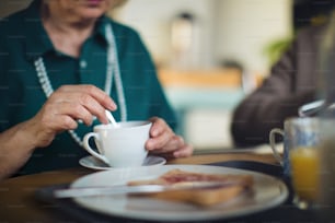 Eine Nahaufnahme einer älteren Frau, die das Frühstück im Pflegeheim genießt.