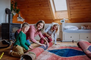Un ragazzo con la sindrome di Down con la madre e la nonna che arrotolano il tappeto di casa.