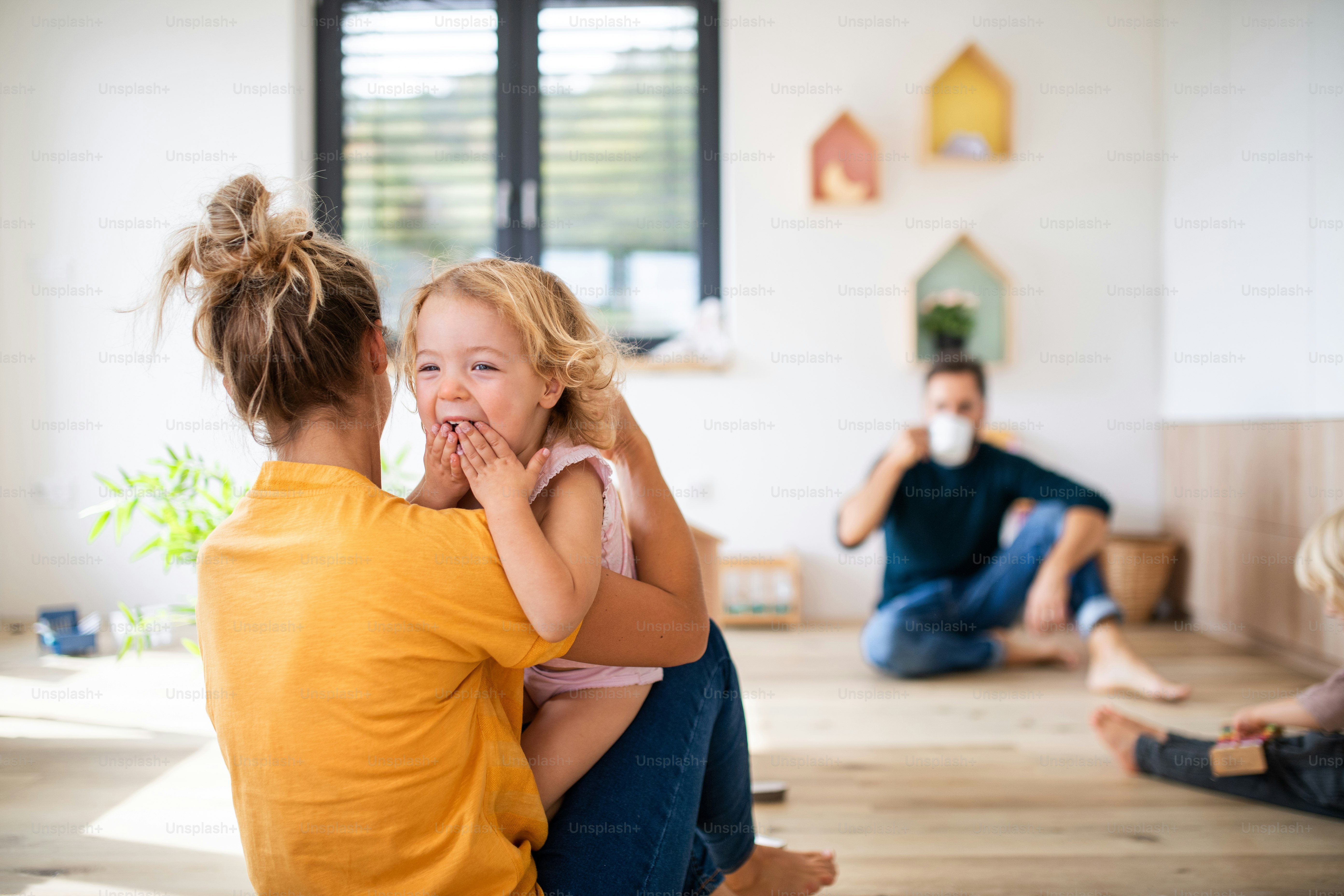 Junge Familie mit zwei kleinen Kindern drinnen im Schlafzimmer, Spaß haben.