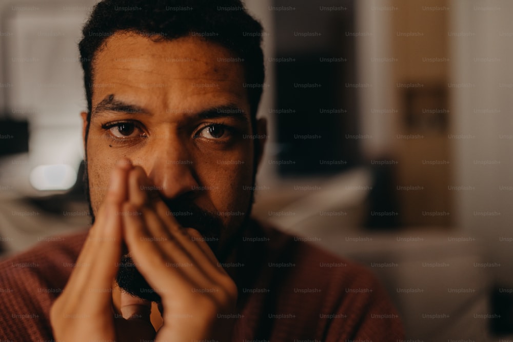 Ein Porträt eines depressiven jungen afroamerikanischen Mannes, der in die Kamera schaut.