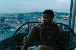 A portrait od depressed young African - American man sitting on balcony with urban view in evening.