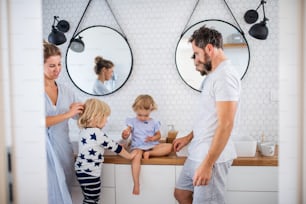 A young family with two small children indoors in bathroom, talking.