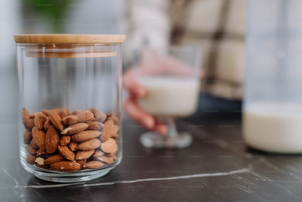 Mandorle e latte di mandorla e un bicchiere sul bancone della cucina. Concetto di prodotto vegano sano.