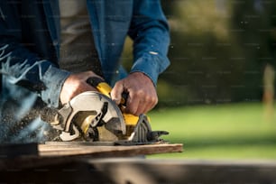 A close-up of raftsman working with circular saw at construction site
