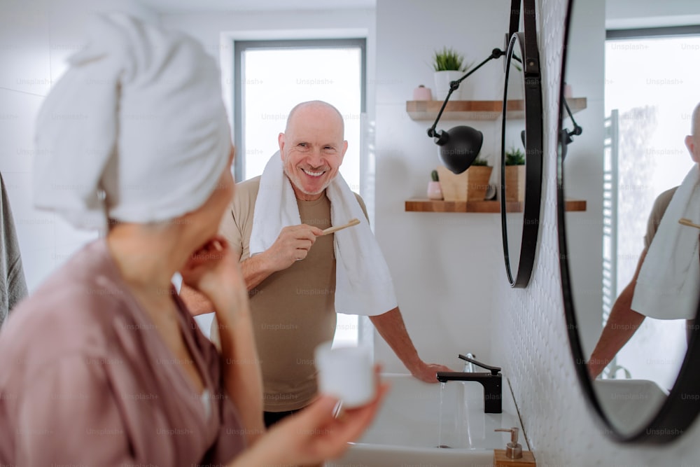 A senior couple in bathroom, brushing teeth and washing, morning routine concept.