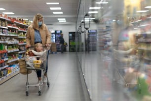 A little girl sitting in the trolley during shopping with mother in hypermarket