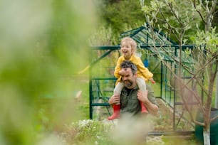 A father with his little daughter bonding in front of eco greenhouse, sustainable lifestyle.