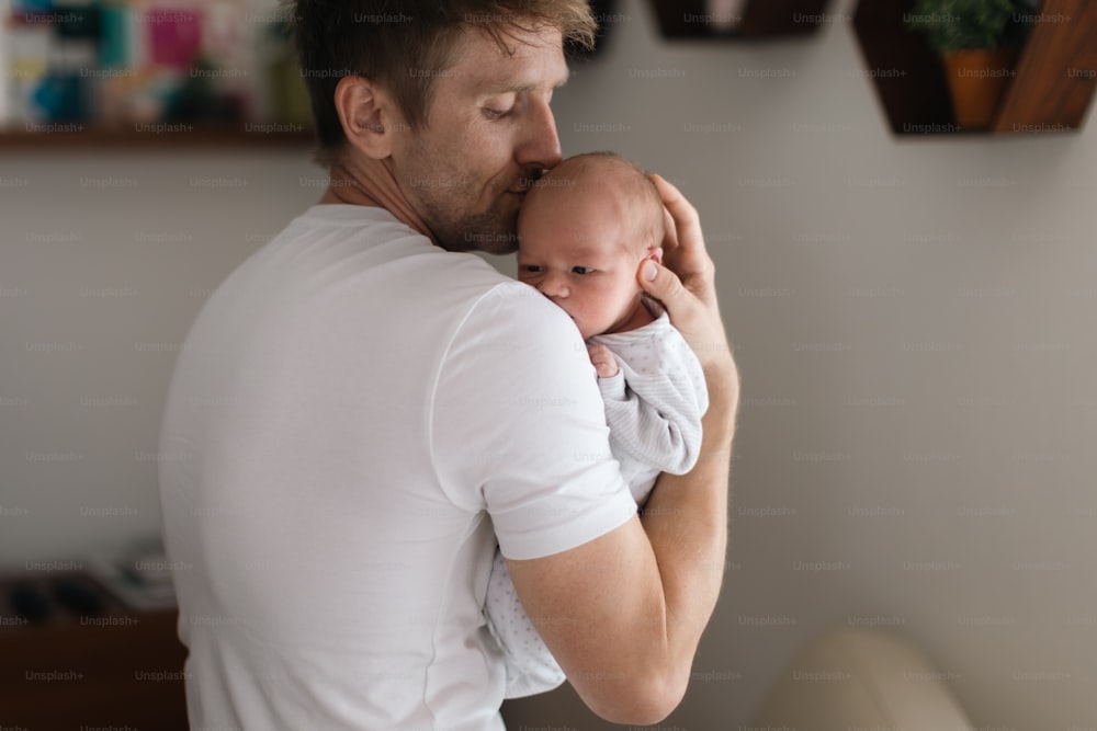 A father holding his newborn son at home.