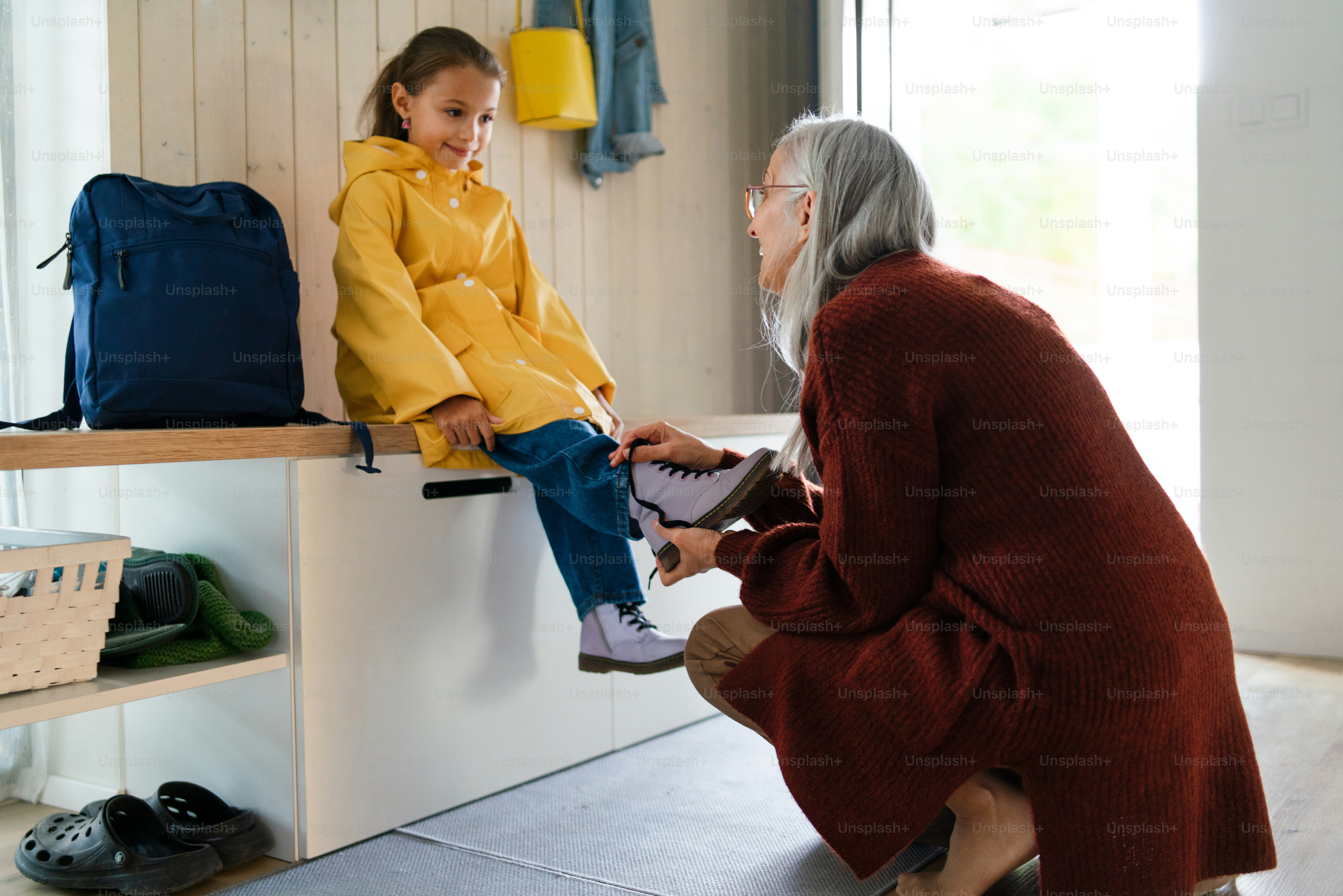 Una nonna che aiuta la nipote a prepararsi per uscire di casa per andare a scuola.